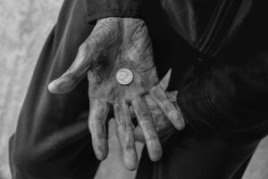 Wrinkled hand holds coin