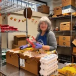 Mary Roberts, a volunteer at Mercy Brown Bag Program, stocks shelves with food items, ensuring seniors have access to essentials.